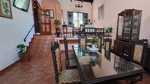A dining area with a glass table and ornate chairs, a staircase, and a large mirror. - The Orchid Hotel (Antigua Guatemala)