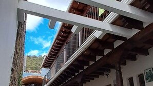 A courtyard with a stone pathway, a wooden pergola, and a view of a mountain. - The Orchid Hotel (Antigua Guatemala)