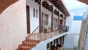 A courtyard with a staircase leading to a covered balcony. - The Orchid Hotel (Antigua Guatemala)