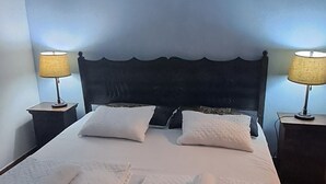 A double bed with white linens and two rolled towels, flanked by nightstands with lamps, in a room with blue walls and a tiled floor. - The Orchid Hotel (Antigua Guatemala)