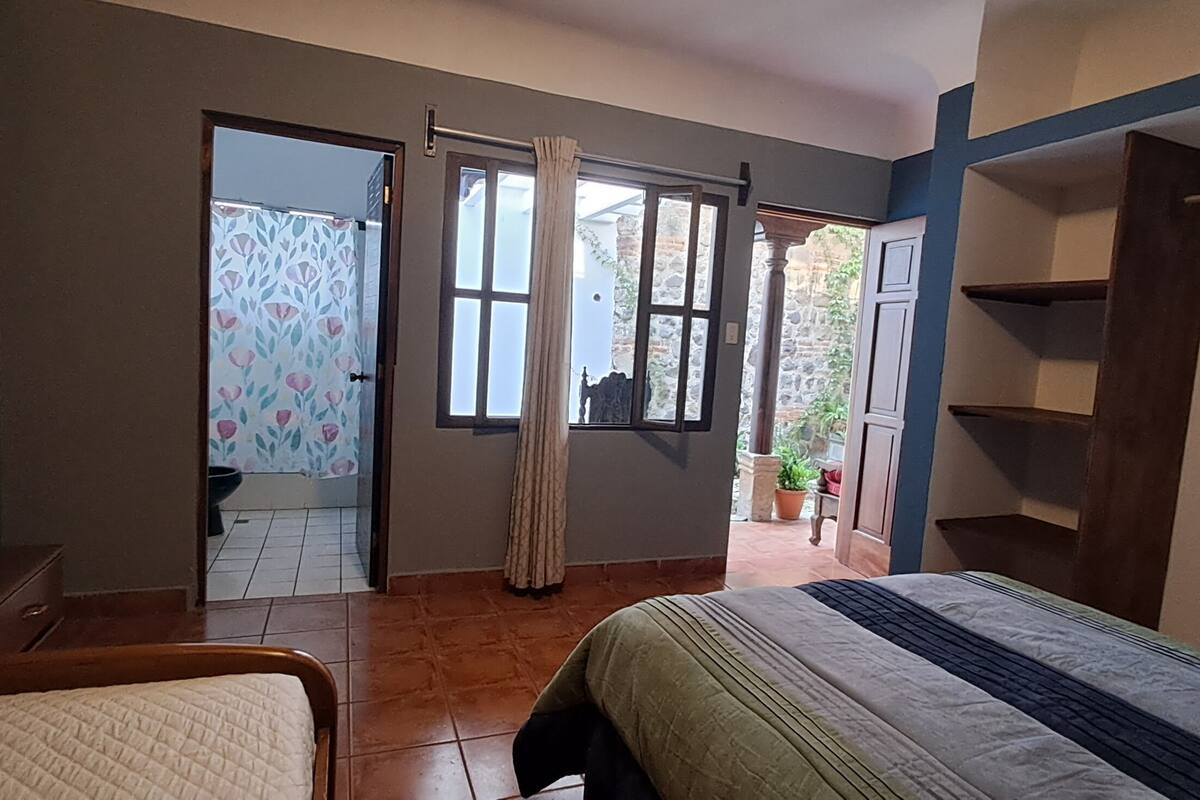 Een slaapkamer met een bed, een kledingkast, een raam en een deur naar een badkamer.