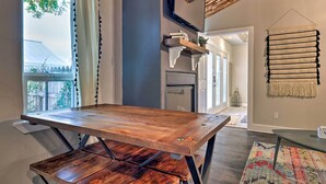 A modern kitchen with a wooden table, a hanging shelf with books, and a view of the outdoors. - Fredericksburg 'regan Cottage' w/ Hot Tub! (Fredericksburg)