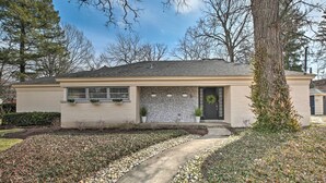 A single-story house with a front porch, a stone facade, and a small garden with a pathway leading to the entrance.