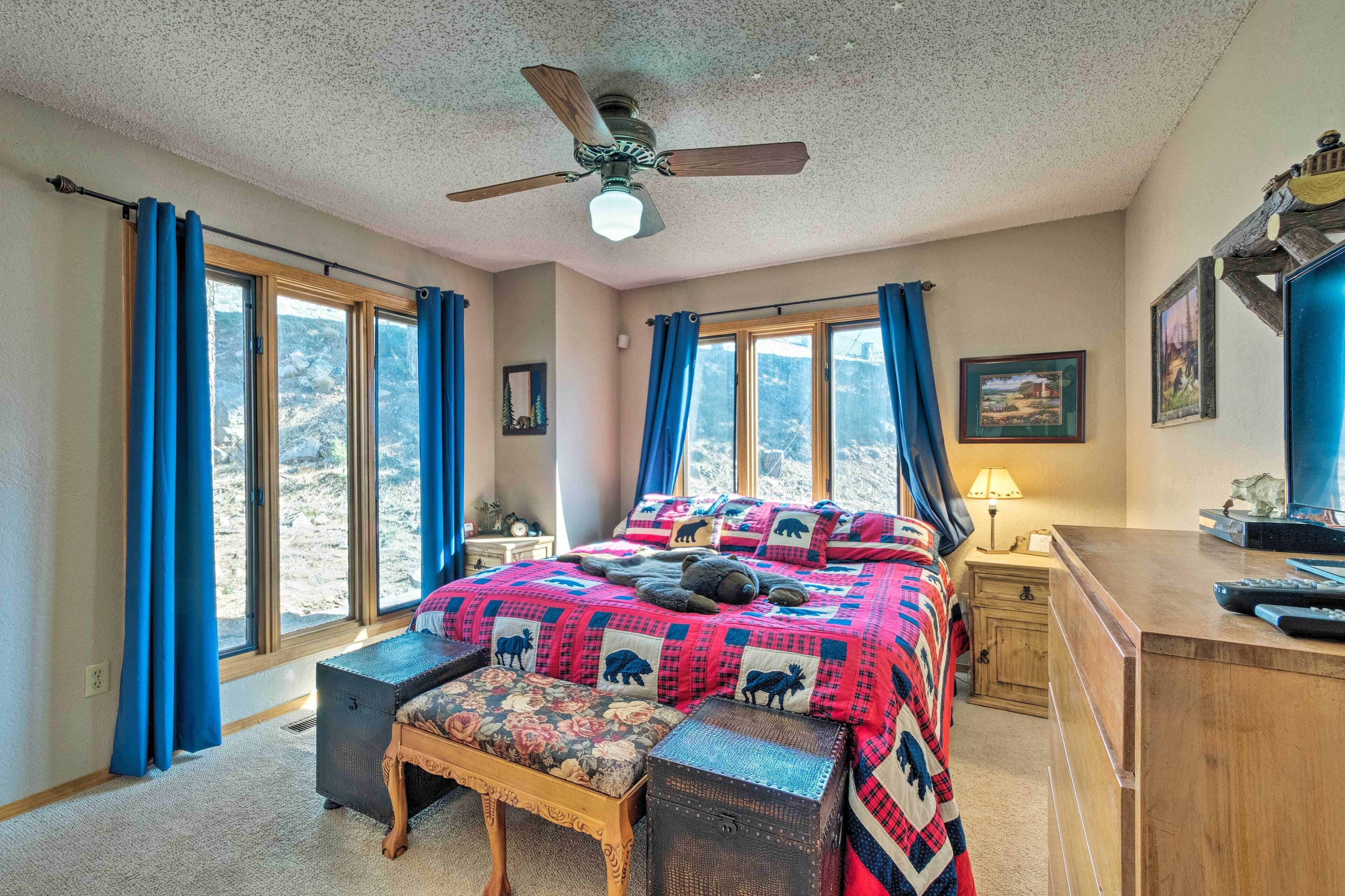 A bedroom with a large bed, a wooden desk, and a ceiling fan.