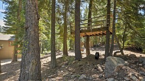 Eine Holzterrasse in bewaldeter Landschaft, im Hintergrund ein Haus.