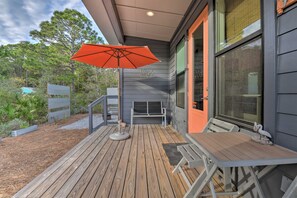 A wooden deck with a table and chairs, an umbrella, and a bench.