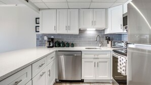 Een moderne keuken met witte kasten, een roestvrijstalen vaatwasser, een inbouwoven en een magnetron.