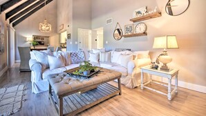 Un salon spacieux avec un canapé blanc, une table basse en bois et une lampe.