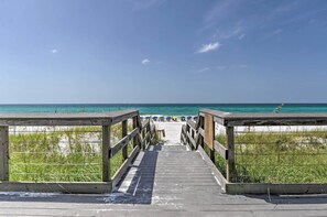 A wooden boardwalk leading to a beach with clear blue water and a few umbrellas. - Resort Condo: Golf & Pond View, Walk to Beach (Miramar Beach)
