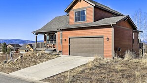 A two-story house with a front porch, a garage, and a clear view of the mountains in the background. - Ski-in/out Granby Home w/ Gas Grill & Fire Pit! (Granby)