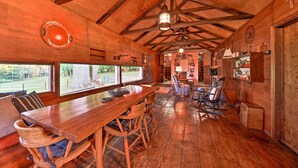 A rustic wooden interior with a large dining table, wooden chairs, and a view of the outdoors. - Custom-built Lakefront Cottage w/ Spacious Yard! (Westford)
