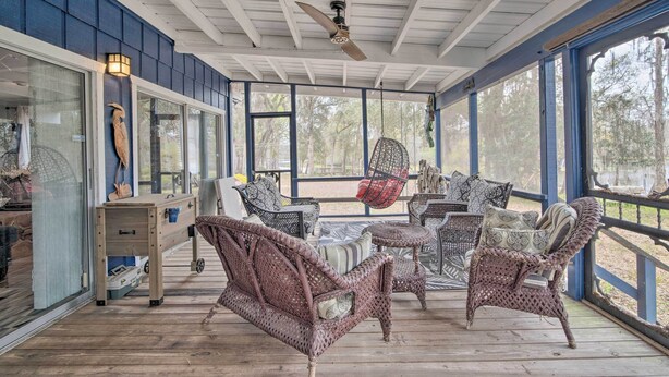 A covered porch with wicker furniture, a ceiling fan, and large windows. - Riverfront Retreat w/ Patio in Withlacoochee (Bushnell)