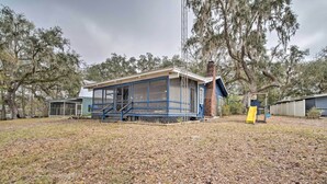 A single-story building with a covered porch, a chimney, and a yellow slide. - Riverfront Retreat w/ Patio in Withlacoochee (Bushnell)