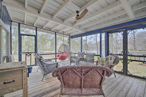 A covered outdoor area with wicker furniture, a ceiling fan, and large windows. - Riverfront Retreat w/ Patio in Withlacoochee (Bushnell)