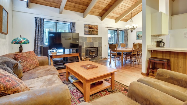 A cozy living room with a fireplace, wooden ceiling beams, a television, and a dining area with chairs and a table. - Mammoth Lakes Condo ~ 5 Mi to Mammoth Mtn! (Mammoth Lakes)