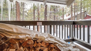 A covered wooden deck with a stack of firewood and a smoking sign. - Mammoth Lakes Condo ~ 5 Mi to Mammoth Mtn! (Mammoth Lakes)