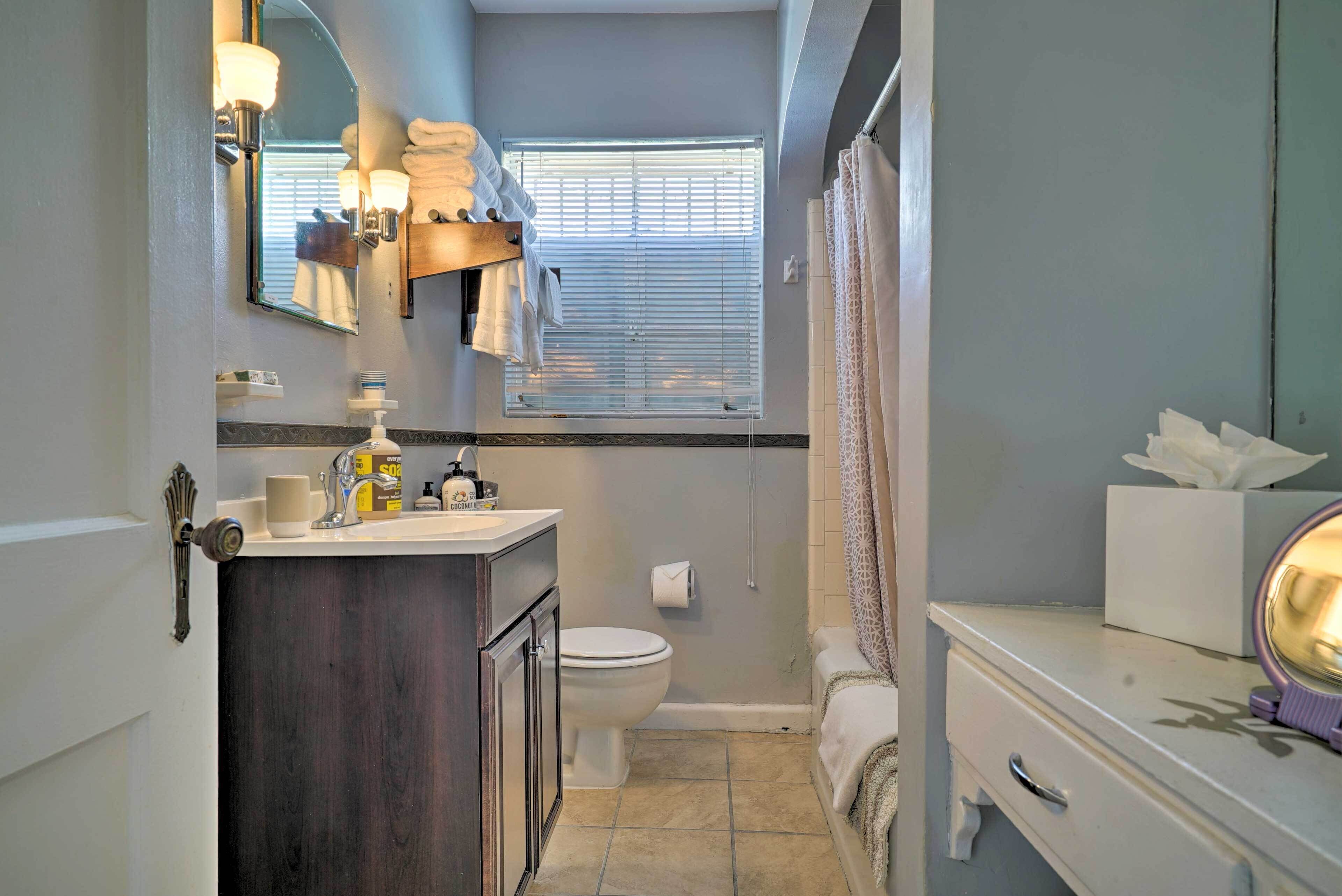 A compact bathroom with a vanity, toilet, and a window with blinds.
