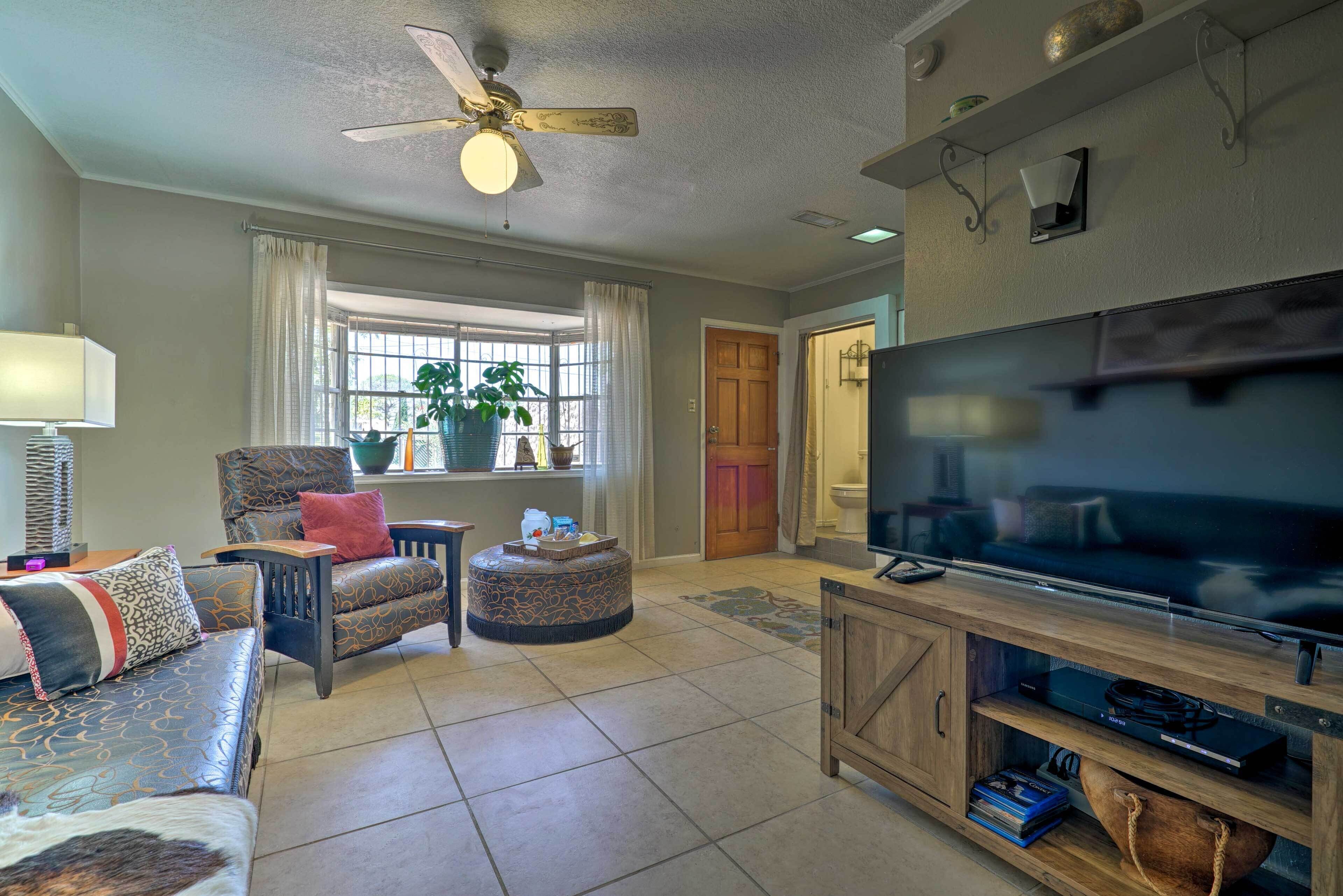 A living room with a ceiling fan, a large flat-screen TV, a sofa, a chair, and a coffee table.