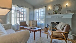 A living room with a fireplace, a sofa, a chair, and a coffee table. - El Paso Home w/ Backyard + Outdoor Fireplace! (El Paso)