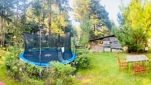 A backyard with a trampoline, swing set, and a small table with chairs. - RANCHO CUMBRE MONARCA  (Ocampo)