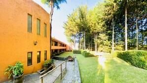 A courtyard with a building featuring a curved facade and multiple windows. - RANCHO CUMBRE MONARCA  (Ocampo)