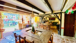 A rustic dining area with a large wooden table and chairs, a small Christmas tree, and a view of the outdoor patio area. - RANCHO CUMBRE MONARCA  (Ocampo)