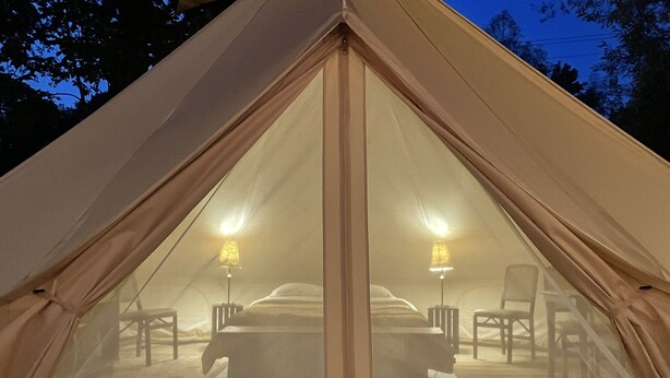 A tent with a bed and two lamps.