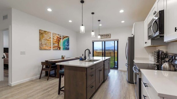 Una cocina moderna con una isla central, iluminación colgante y vistas al exterior.