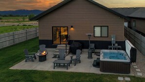 Una casa moderna con un patio, mobiliario exterior, un jacuzzi y una chimenea.