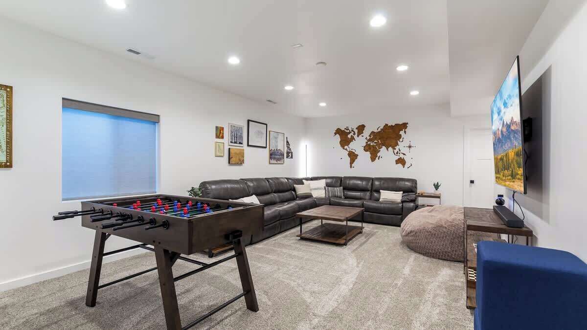 Een moderne woonkamer met een tafelvoetbaltafel, een leren bank, een salontafel en een wereldkaart aan de muur.