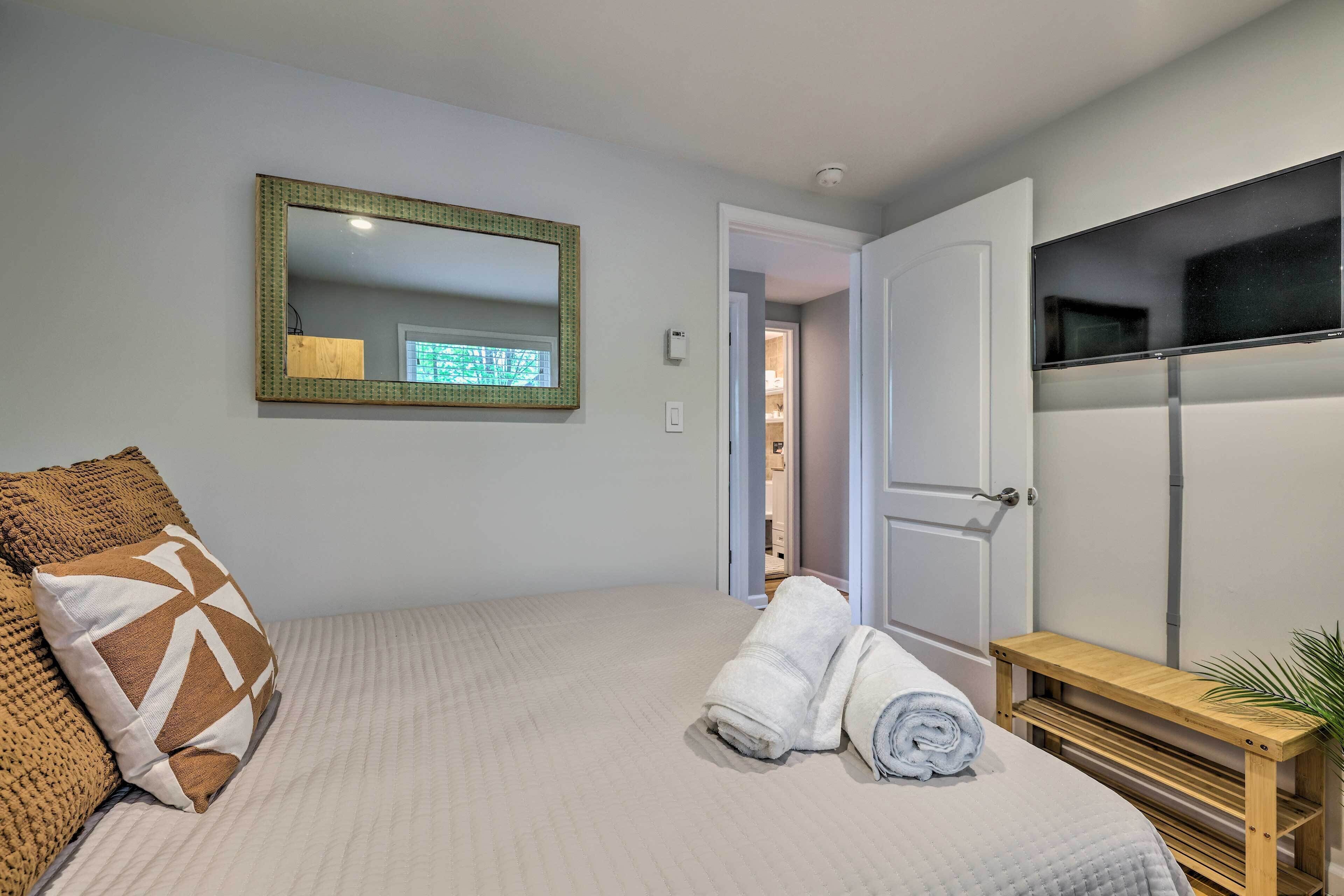 A bedroom with a bed, a mirror, a wooden bench, and a towel.