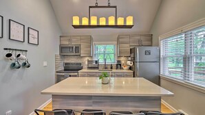 Una cocina moderna con una isla central, electrodomésticos de acero inoxidable y un ventanal grande.
