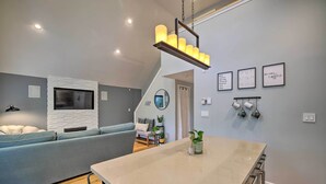 Una cocina moderna con una isla central, estufa integrada y una lámpara colgante.