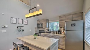 Una cocina moderna con una isla central, electrodomésticos de acero inoxidable y una lámpara colgante.