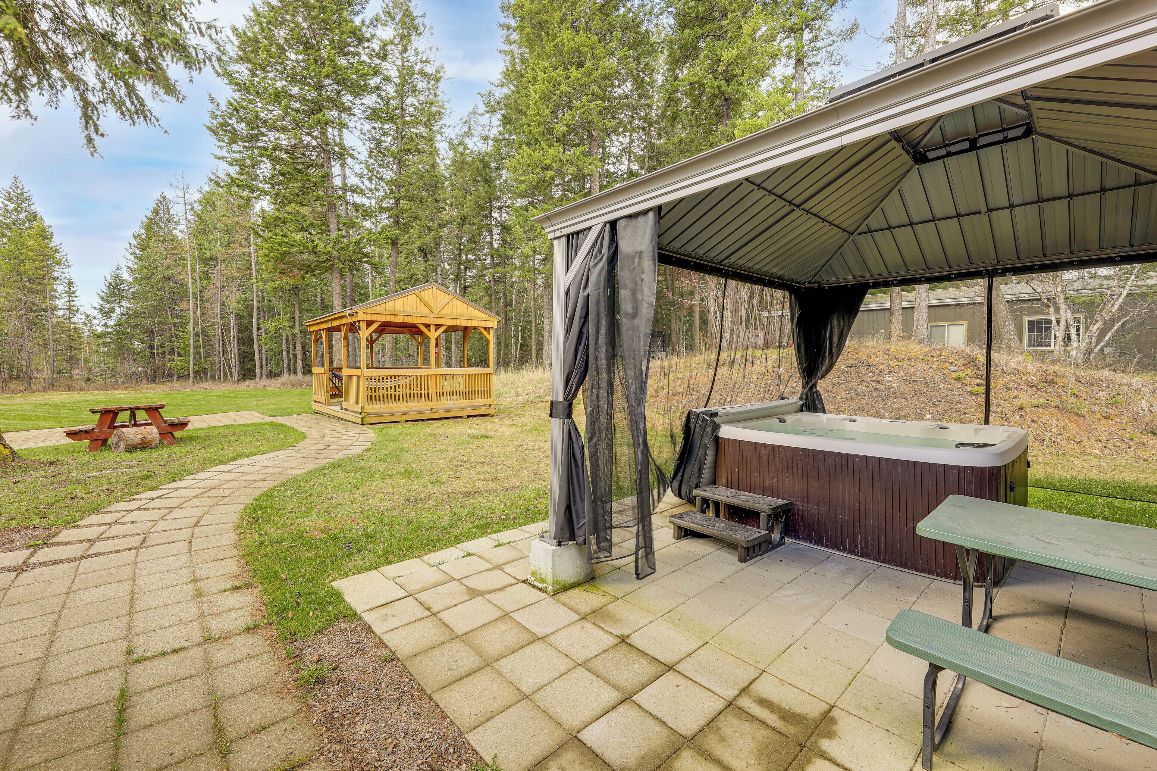Ein überdachter Außenbereich mit Whirlpool, Picknicktischen und einem Holzpavillon.