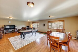A spacious living room with a pool table, a dining area with wooden chairs, a television, and a fireplace. - Columbia Falls Private Retreat: Pool Table & Deck! (Columbia Falls)
