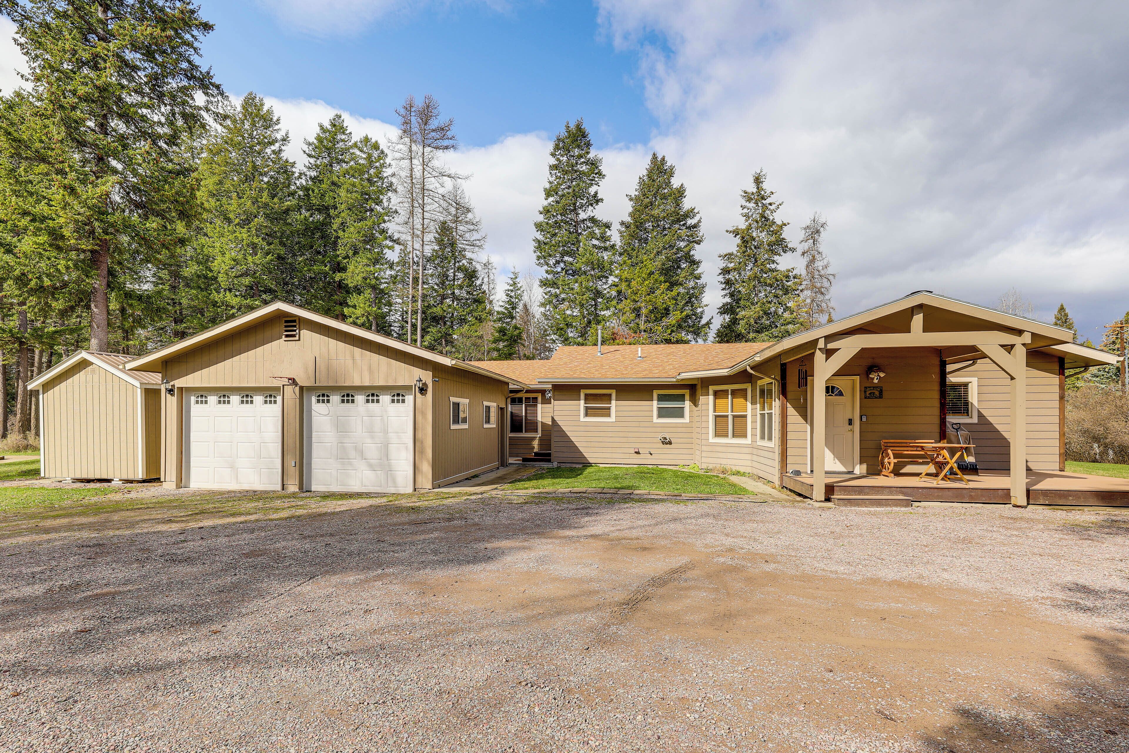 A two-story house with a garage, a covered porch, and a gravel driveway.
