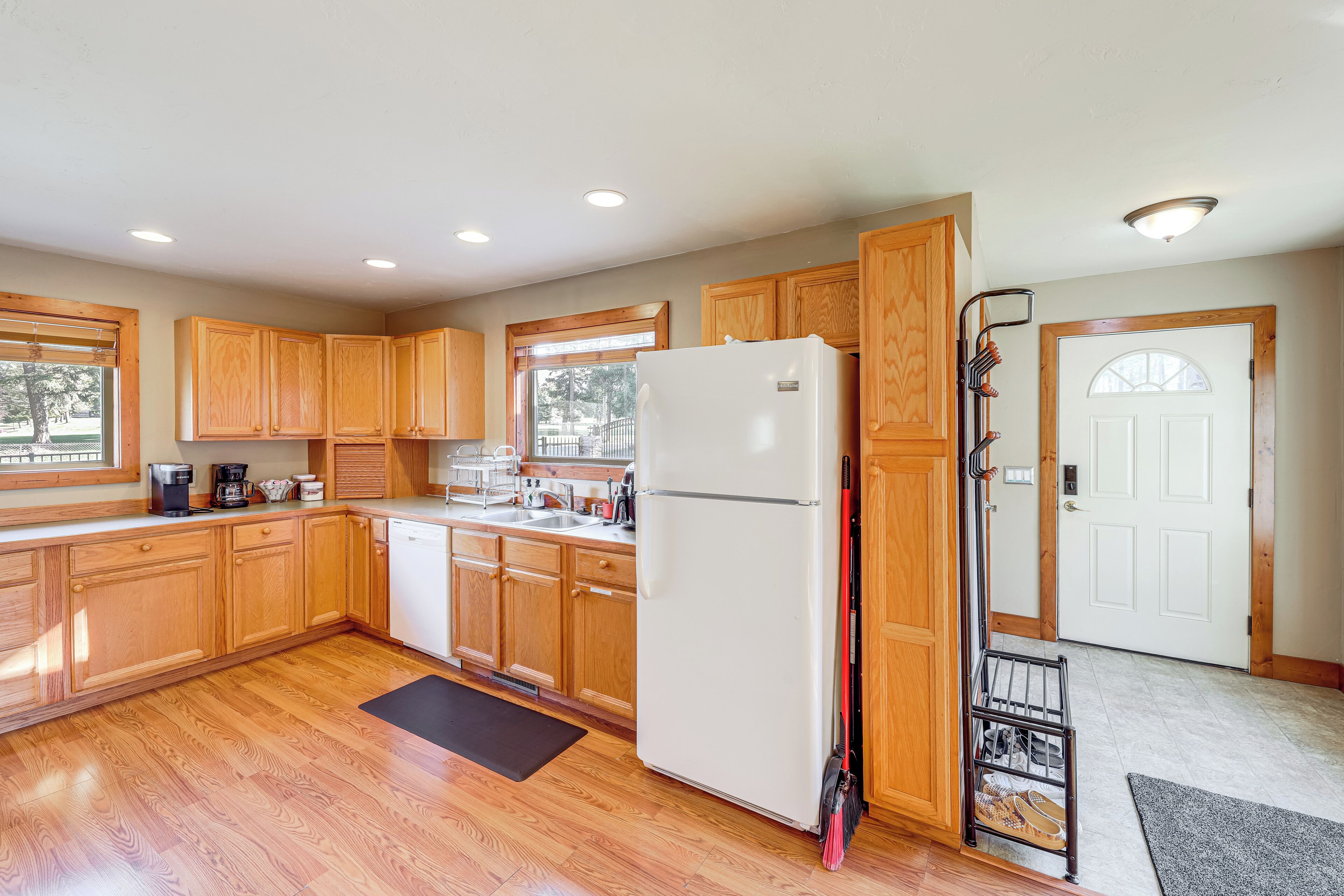 A kitchen with wooden cabinets, a white refrigerator, and a broom leaning against the wall.
