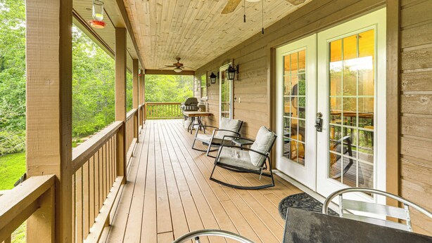 A wooden deck with rocking chairs and a table, overlooking a green landscape. - 'creekside Hideaway' w/ Fire Pit + Creek Access! (Mountain View)