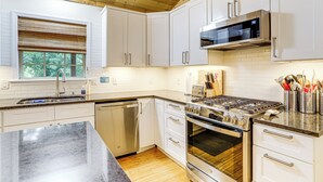 A modern kitchen with white cabinets, stainless steel appliances, and a granite countertop. - 'creekside Hideaway' w/ Fire Pit + Creek Access! (Mountain View)