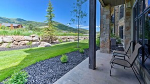Un patio con mobiliario exterior, muros de piedra y vistas a un paisaje montañoso.