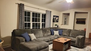 A living room with a sectional sofa, a coffee table, and a large window with curtains. - Private DC Hideaway ten minutes from beaches! (Sturgeon Bay)