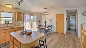 Una cocina con armarios de madera, una isla grande y un comedor con sillas.