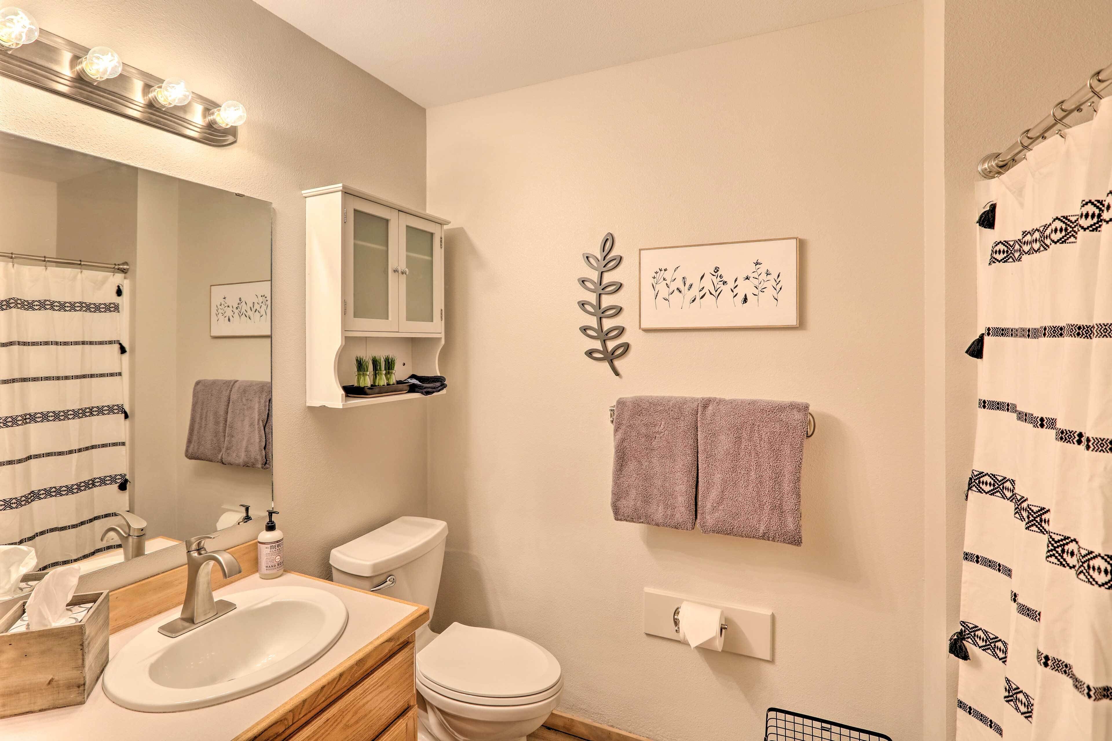 Een badkamer met een wastafel, spiegel, kastje, toilet en handdoekhouder.