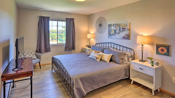 A bedroom with a bed, bedside tables, a desk, a chair, and a window with curtains.
