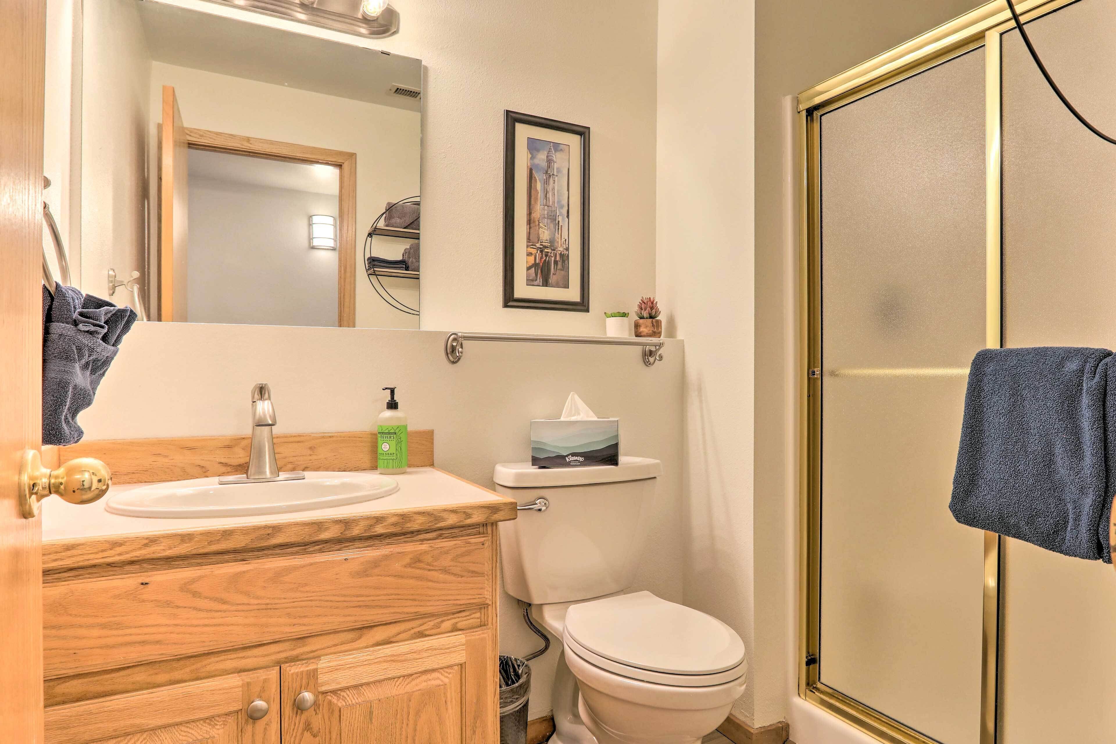 A bathroom with a wooden vanity, a sink, a toilet, and a shower.