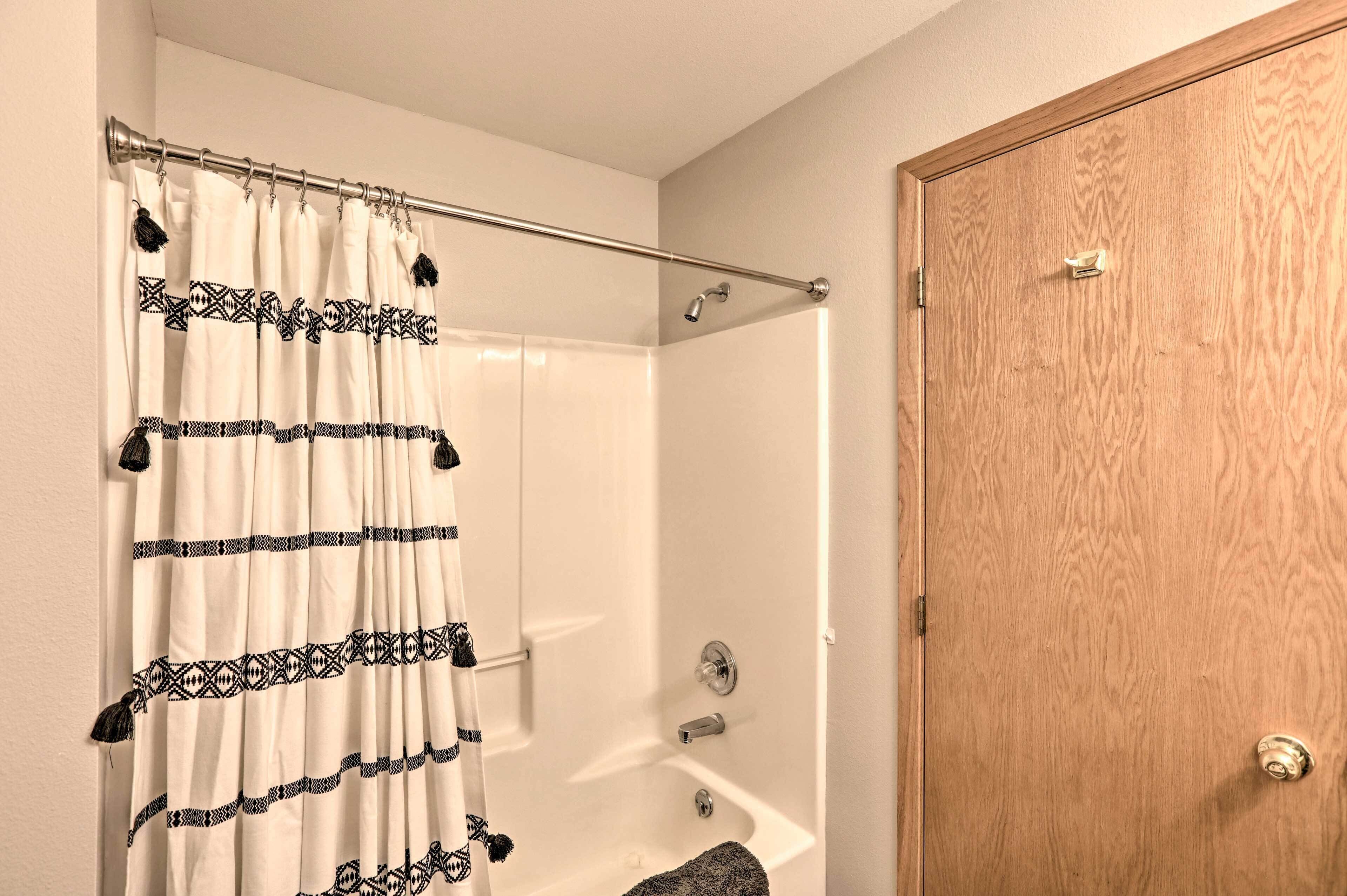 A bathroom with a bathtub, a shower curtain, and a wooden door.