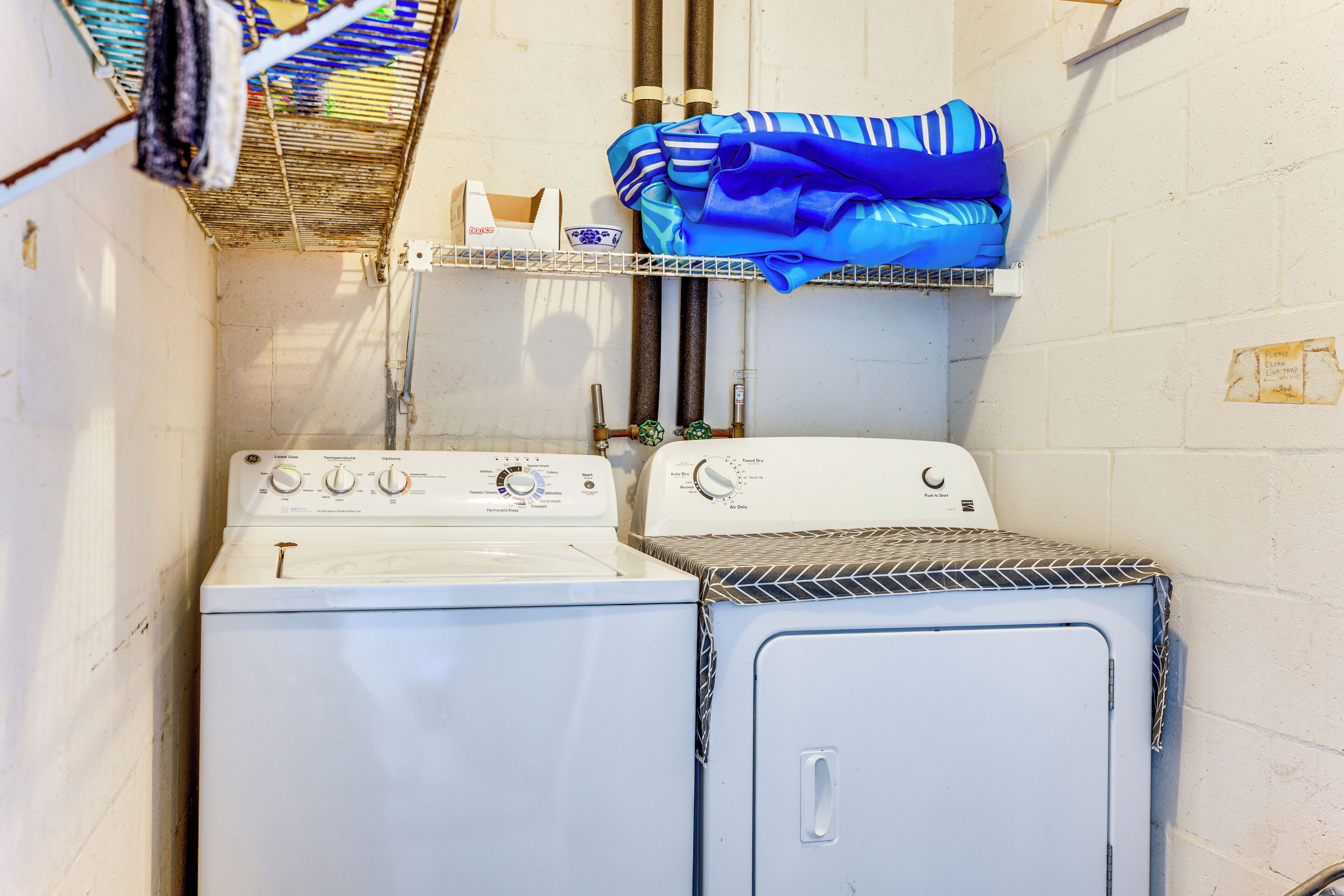 A laundry area with two washers and dryers, a shelf with folded clothes, and a wall-mounted rack.