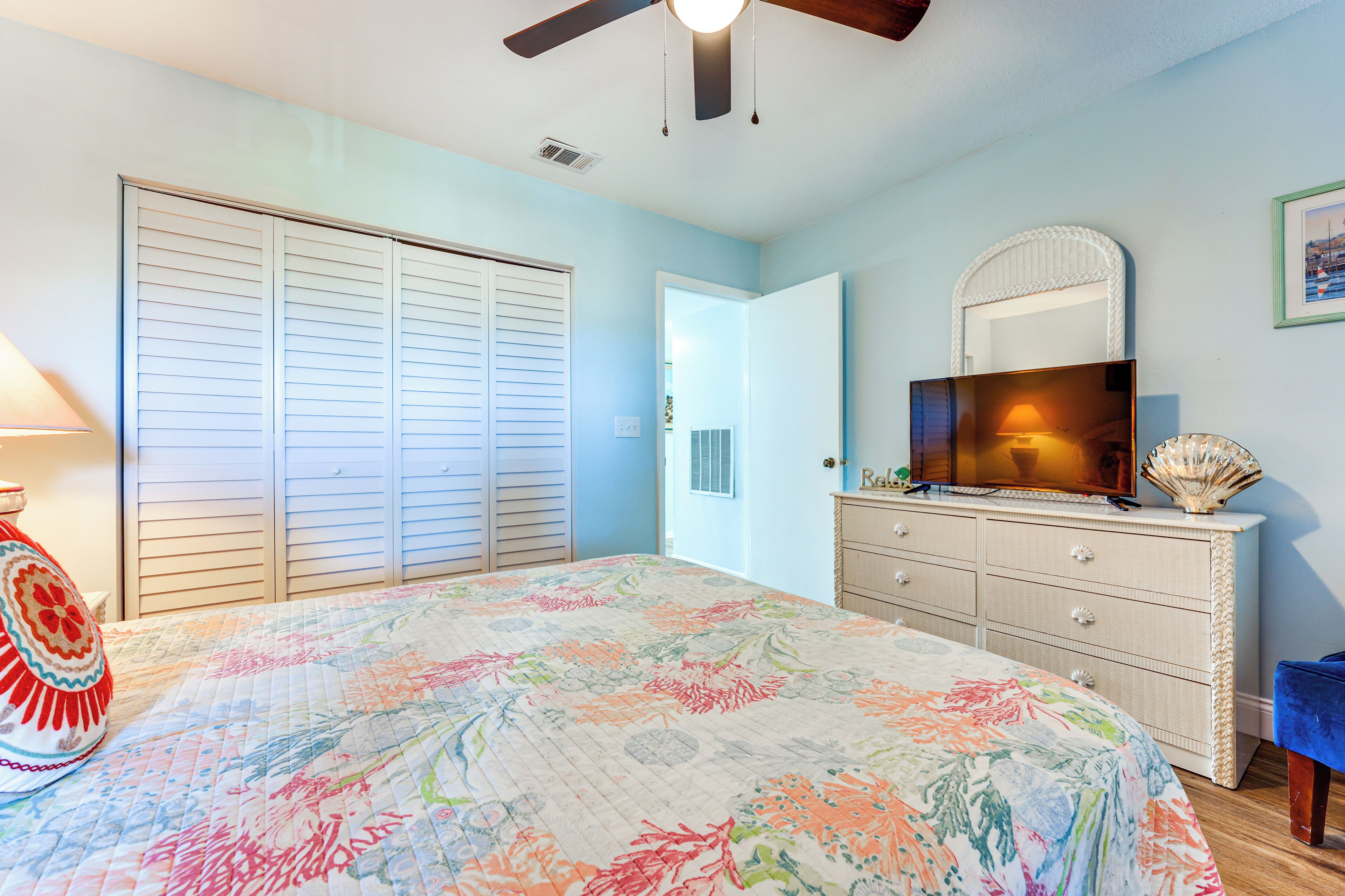 A bedroom with a bed, a dresser, a television, and a closet.