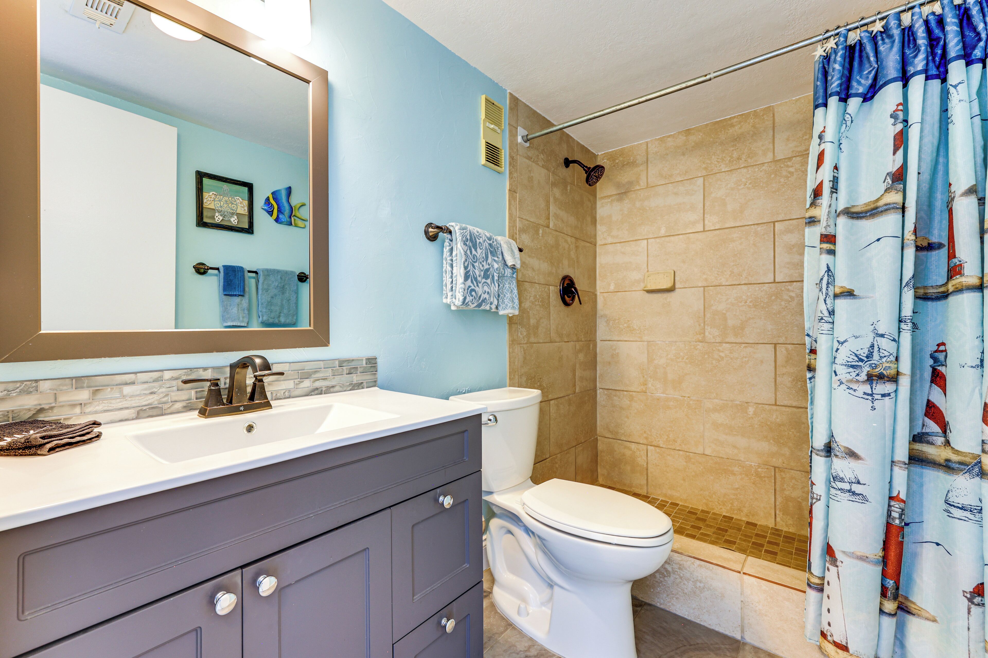 A bathroom with a white sink, a mirror, a toilet, and a shower curtain.